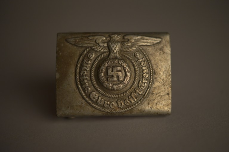 Hebilla metálica de cinturón de las SS nazis, colección del Museo Estatal de Auschwitz-Birkenau Foto por Pawel Sawicki © Auschwitz-Birkenau State Museum - Musealia